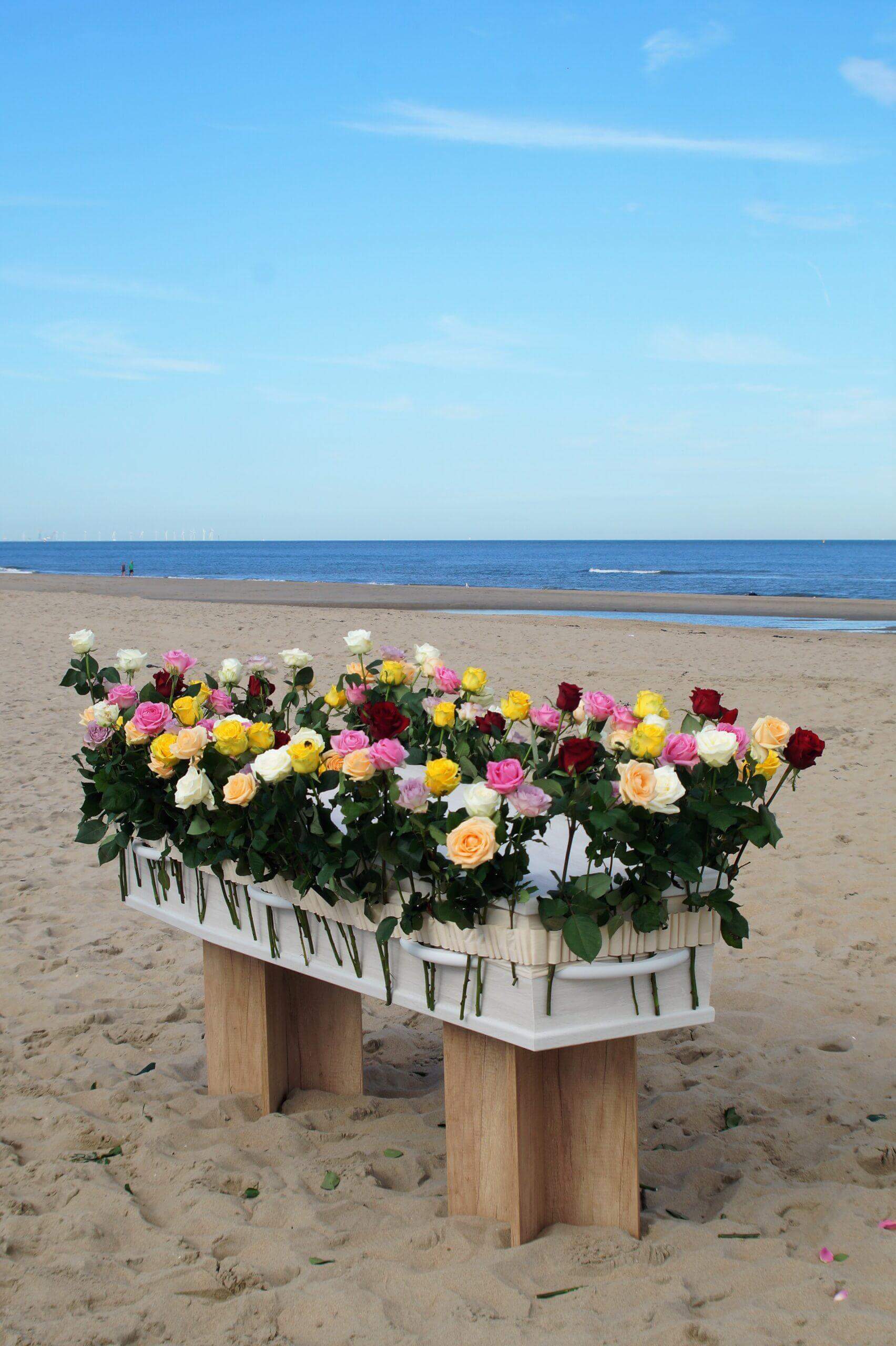 Gedenkwebshop - Bloemenband om kist op het strand
